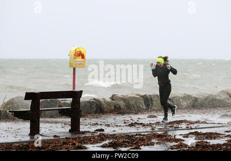 Ein Jogger wird von der Spray auf Salthill Promenade gefangen, Co Galway, während der Sturm Callum. Bild Datum: Freitag, 12. Oktober 2018. Siehe PA Geschichte Wetter Callum. Photo Credit: Brian Gesetzlosen/PA-Kabel Stockfoto