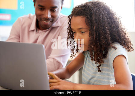 Lehrer mit der Grundschule Mädchen am Laptop arbeiten Stockfoto