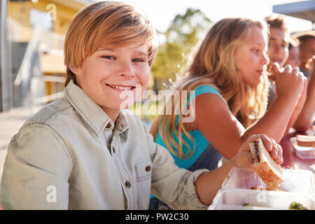 Junge an der Volksschule Mittagstisch lächelnd in die Kamera Stockfoto