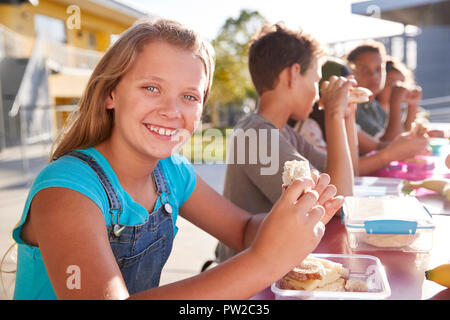 Mädchen in der Grundschule Mittagstisch lächelnd in die Kamera Stockfoto