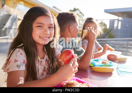 Mädchen in der Grundschule Mittagstisch lächelnd in die Kamera Stockfoto