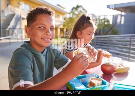 Junge an der Volksschule Mittagstisch lächelnd in die Kamera Stockfoto