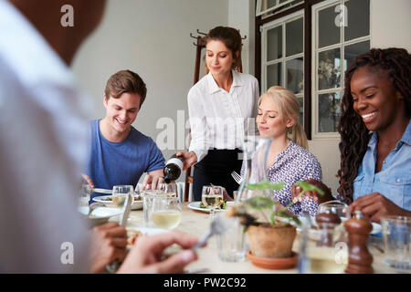 Kellnerin gießen Wein für eine Gruppe von Freunden genießen Essen im Restaurant zusammen Stockfoto