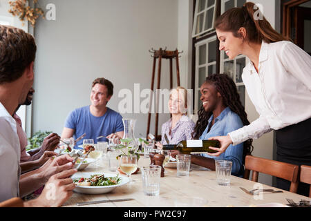 Kellnerin gießen Wein für eine Gruppe von Freunden genießen Essen im Restaurant zusammen Stockfoto