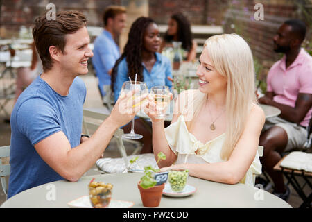 Paar am Tisch in der Kneipe Garten einen Toast zusammen sitzen Stockfoto