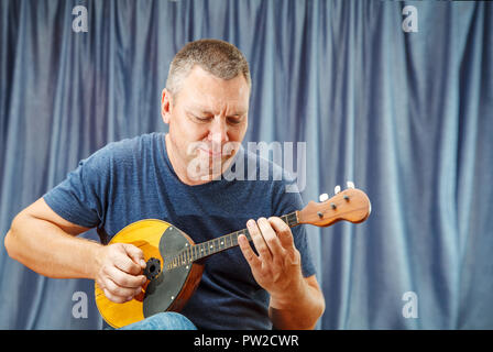 Ältere Mann spielt die Mandoline indoor mit hellem Tageslicht Stockfoto