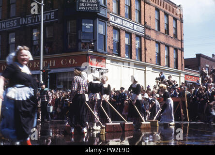 1940 s, historischen, amerikanische Frauen in Kostümen mit Bürsten in der Straße, die möglicherweise "Tulip" Festival in der Stadt von Holland, Michigan, USA, eine Feier der Niederländischen Erbe der Stadt. Durch die Niederländische Calvanist Siedler im Jahre 1847 gegründet, ist die Stadt zu einem Vorposten der niederländischen Kultur und Tradition in der Mitte des amerikanischen Mittleren Westen und ist bekannt für seine Kirchen, von denen Sie sind ca. 170 im Großraum Holland, bekannt. Stockfoto