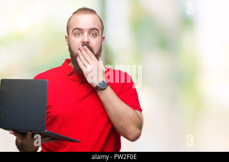 Jungen kaukasischen Mann mit Computer Laptop über isolierte Hintergrund decken den Mund mit der Hand schockiert mit Schande für den Fehler, den Ausdruck von Angst, Angst Stockfoto