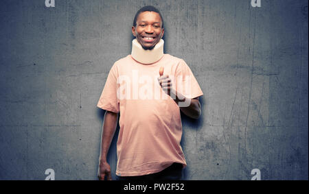 Afrikanischen schwarzen Mann, Neck Brace lächelte breit Daumen hoch, Geste, die Kamera, den Ausdruck von wie und Genehmigung verletzt Stockfoto