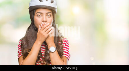 Junge arabische Radfahrer Frau tragen Schutzhelm über isolierte Hintergrund für Mund mit den Händen für den Fehler schockiert. Geheime Konzept. Stockfoto