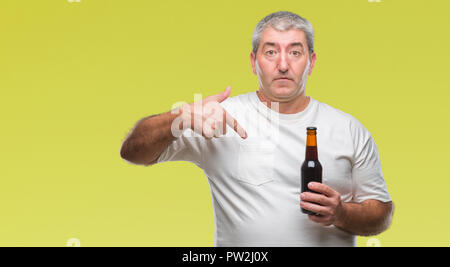 Schöne ältere Menschen trinken Bier Flasche über isolierte Hintergrund mit Überraschung Gesicht zeigenden Finger zu sich selbst Stockfoto