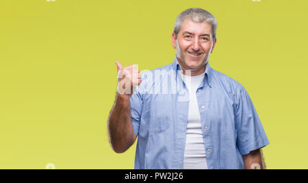 Gut aussehender älterer Mann über isolierte Hintergrund lächelnd mit glücklichen Gesicht und zeigt auf die Seite mit dem Daumen nach oben. Stockfoto