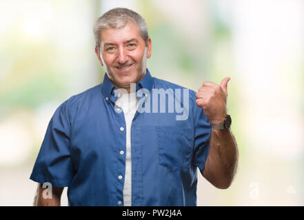 Gut aussehender älterer Mann über isolierte Hintergrund lächelnd mit glücklichen Gesicht und zeigt auf die Seite mit dem Daumen nach oben. Stockfoto