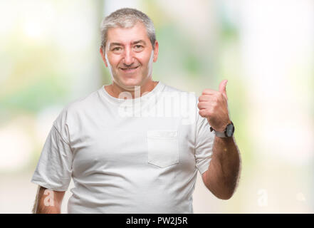 Gut aussehender älterer Mann über isolierte Hintergrund lächelnd mit glücklichen Gesicht und zeigt auf die Seite mit dem Daumen nach oben. Stockfoto