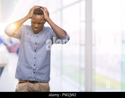 Junge afrikanische amerikanische Mann mit blauem Hemd Kopfschmerzen leiden, verzweifelte und betonte, weil Schmerz und Migräne. Hände auf den Kopf. Stockfoto