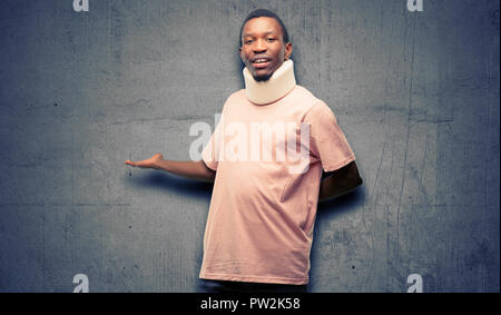 Verletzte afrikanischen schwarzen Mann, Neck Brace zuversichtlich und zufrieden mit einen großen natürlichen Lächeln einladenden eingeben Stockfoto