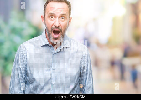 Mittleres Alter hoary Senior Business Mann über isolierte Hintergrund Angst und mit Erstaunen Ausdruck, Angst und aufgeregt Gesicht schockiert. Stockfoto