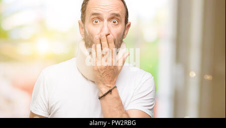 Verletzte älterer Mann mit einem Neck Brace deckt Mund in Schock, blickt schüchtern, Stille und Fehler Konzepte, Angst Stockfoto