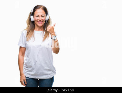 Mittleres Alter Hispanic Frau Musikhören mit Kopfhörern über isolierte Hintergrund tun glücklich Daumen nach oben Geste mit der Hand. Die Genehmigung der Ausdruck Stockfoto
