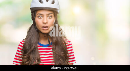 Junge arabische Radfahrer Frau tragen Schutzhelm über isolierte Hintergrund Angst und mit Erstaunen Ausdruck, Angst und aufgeregt Gesicht schockiert. Stockfoto