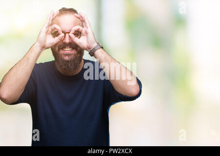 Junge kaukasier hipster Mann Sonnenbrille tragen über isolierte Hintergrund tun ok Geste wie Fernglas Zunge heraus, Augen durch Fin suchen Stockfoto