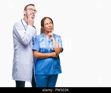 Mittleres Alter spanischer Ärzte Partner Paar mit medizinischen gleichmäßig über isolierte Hintergrund mit der Hand am Kinn über die Frage nachdenken, nachdenklich Expres Stockfoto