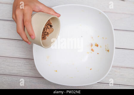 Gießen brauner Zucker in die Schüssel mit den Zutaten für die Herstellung von Cookies Stockfoto