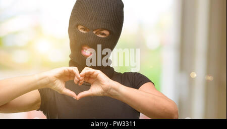Einbrecher terroristischen Frau mit Sturmhaube ski Maske glücklich Liebe mit Händen in Herzform zum Ausdruck gesund und ehe Symbol Stockfoto
