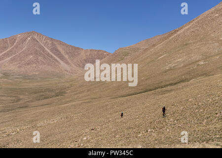 Trekker Abstieg von 4.800 m Bel Airyk Pass mit Zorkul See im Hintergrund auf Trek von Keng Shiber Kara Jilga, Pamir, Tadschikistan. Stockfoto