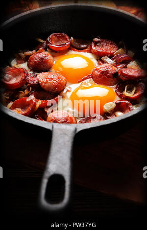 Gekochte Eier und Würstchen auf rying Pan, leckeres englisches Frühstück auf hölzernen Hintergrund Stockfoto