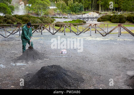 Ein Mann, der ein Loch in Fumarolis da Lagoa das Furnas für Cozido das Furnas auf der Insel Sao Miguel auf den Azoren, Portugal, grub Stockfoto