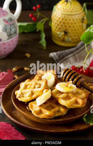 Thanksgiving backen. Belgische Nussbaum Wafer auf einer hölzernen Küchentisch, serviert mit frischem Bananenscheiben und Honig. Stockfoto