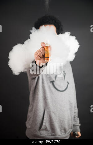 Vape Konzept. Rauchschwaden und vape liquid Flaschen auf dunklem Hintergrund. Nützlich als Hintergrund- oder vape Werbung oder vape Hintergrund. Stockfoto