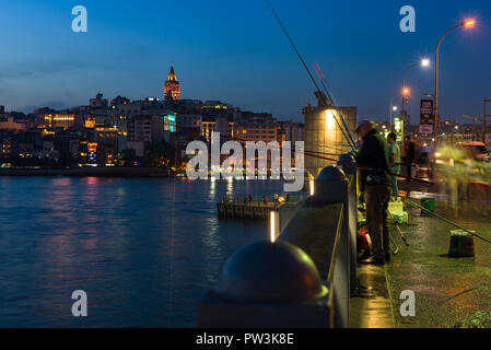 Ein Fischer Fische von der Galatabrücke bei Sonnenuntergang mit Galata Turm und Karakoy im Hintergrund, Istanbul, Türkei Stockfoto