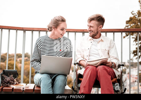 Fröhliche Frau mit Laptop und behinderte Menschen sein Notebook Holding Stockfoto