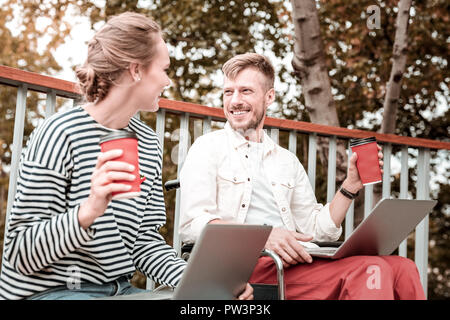 Gerne Freunde holding Laptops und trinken Kaffee im Park Stockfoto