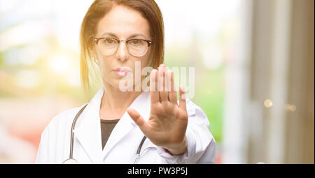 Arzt Frau, medizinischer Fachmann mit schlechter Haltung, STOP-Schild mit Hand genervt, nein zu sagen, und die Sicherheit, die Verteidigung oder Beschränkung, vielleicht Stockfoto