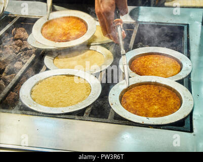 Kunefe, auch als Kenafeh, einem traditionellen arabischen Dessert mit Kadayif, einem dünnen Teig Nudel, über Holzkohle Grill eines Straße bekannt. Istanbul. Stockfoto