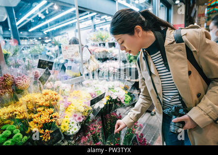 Hübsche Frau Wahl Blumen außerhalb der Flower Shop in den traditionellen Markt. Japanische junge Dame der Wahl Dekoration im Blumengeschäft speichern. c Stockfoto