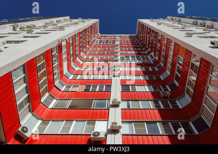 Anzeigen eines Wohnhauses von unten nach oben. Weißes Haus mit roten Balkone in einem warmen sonnigen Tag. Stockfoto