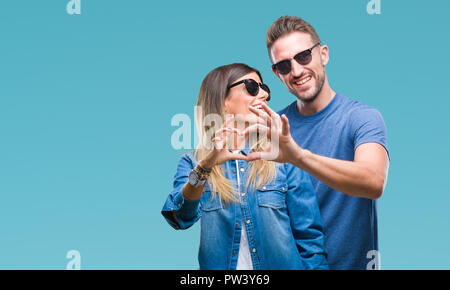 Junges Paar in Liebe Sonnenbrille tragen über isolierte Hintergrund in der Liebe mit Herz und mit Hand lächelnd. Romantische Konzept. Stockfoto