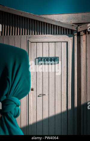 Details von den schönen weißen Strand Hütten in Europa. Windig, sonnigen Tag, blau Schal im Vordergrund, Fertighaus minimalistisch Unterstände im Hintergrund. Ruhiger Stockfoto