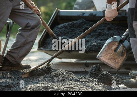 Arbeitnehmer Anwendung Kies und Zement zu einem Stoß in der Straße neue Asphaltdecke zu machen. Stockfoto