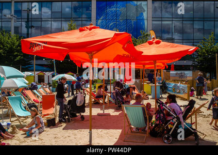 Eltern und Mitarbeiter gleichermaßen genießen Sie die Sonne und die erste Gebaut' Strand entspannen" in der neuen kulturellen Viertel in der Mitte des C Stockfoto