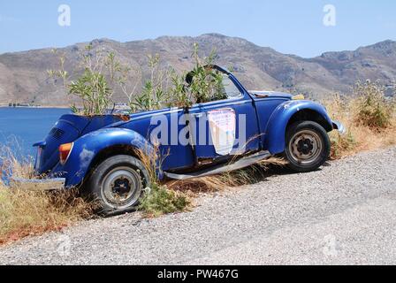 Eine alte verlassene Volkswagen Beetle Auto mit Sträuchern wachsenden innen am Livadia auf der griechischen Insel Tilos am 15. Juni 2018. Stockfoto