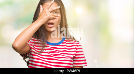 Junge schöne arabische Frau über isolierte Hintergrund peeking im Schock für Gesicht und Augen mit der Hand, schauen durch die Finger mit peinlich Expres Stockfoto