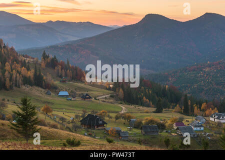 Farbenprächtige Herbstlandschaft im Bergdorf. Nebeliger morgen in den Karpaten, Ukraine Stockfoto