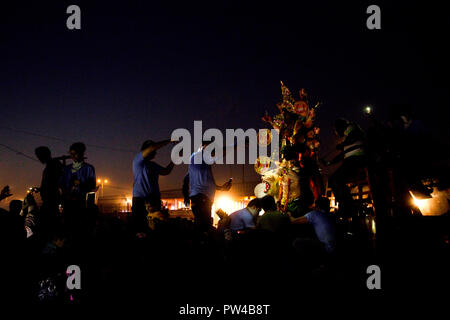 Eine Gruppe von Menschen ist die Beleuchtung Telefon blinkt beim Versuch zu helfen Entladen ein Idol der hinduistischen Göttin Durga anlässlich der Durga Visarjan in Delhi. Stockfoto