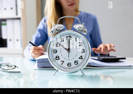 Nahaufnahme von einem Wecker Vor Geschäftsfrau Arbeiten am Arbeitsplatz Stockfoto