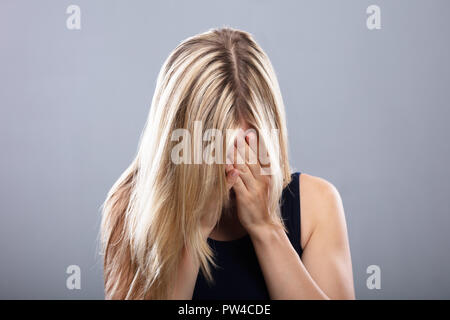 Nahaufnahme von einem weinenden jungen Frau auf grauem Hintergrund Stockfoto
